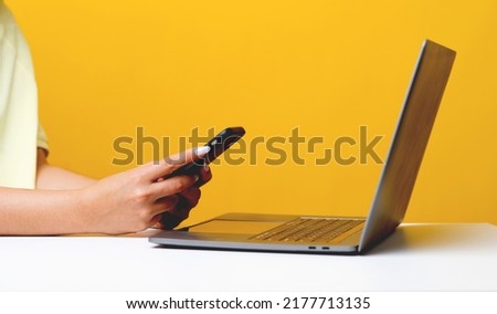 online communication woman using laptop and mobile phone web surfing and online world work at home yellow background communication concept