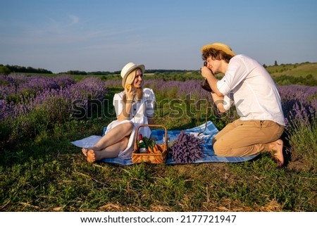 couple in purple lilac outfit have picnic in lavender field, photo session. Romance Royalty-Free Stock Photo #2177721947