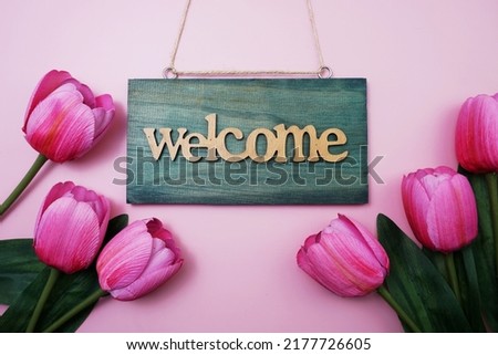 Welcome Sign and Tulip Flower Blooming Decoration on pink background