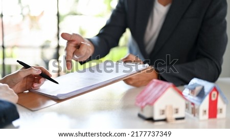 Male real estate agent or realtor and a female client having a meeting to sign the rent contract in the office. cropped and focus hands.