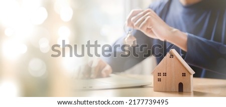 Businessman choosing mini wood house model. Planning to buy property. Choose what's the best. A symbol for construction ,ecology, loan concepts.