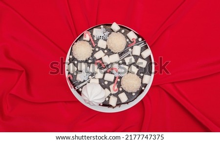 Christmas cake with Xmas decorations on white plate on red tablecloth. Greeting card for holiday dinner with copy space. New Year or Christmas background 
