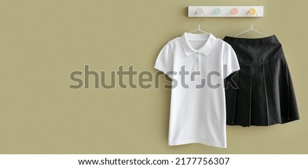 Stylish school uniform hanging on color wall. Banner for design