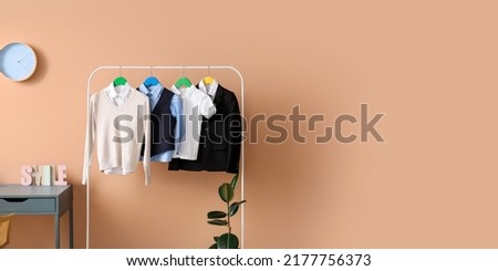 Rack with stylish school uniform near color wall. Banner for design
