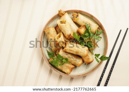 Traditional southeast asian starter dish spring or summer rolls - deep fried dim sum dumplings stuffed with vegetables with soy sauce, fresh coriander on grey plate with black chop sticks, top view Royalty-Free Stock Photo #2177762665