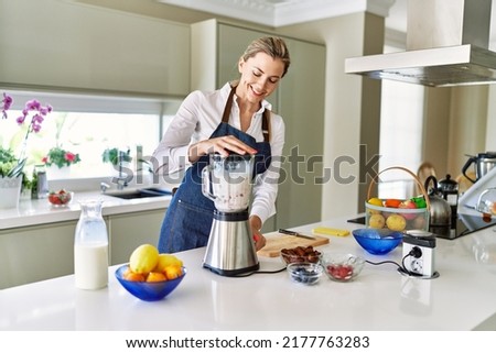 Young blonde woman smiling confident liquefying smoothie using bender at kitchen Royalty-Free Stock Photo #2177763283