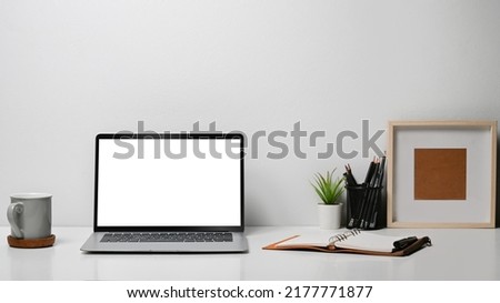 Mock up laptop computer, coffee cup, stationery and picture frame on white table