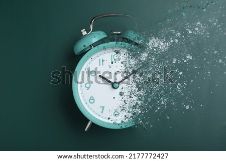 Time is running out. Turquoise alarm clock vanishing on green background, top view Royalty-Free Stock Photo #2177772427