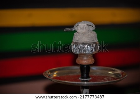 Hookah bowl, hookah bowl with embers on it. Round metal tray, colorful background. selective focus. hookah cafe idea
