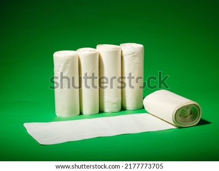 Five rolls of white environmental garbage bags of different sizes on green background. Four rolls stand and one lies unfolded. Business concept on use of secondary raw materials and processing. Royalty-Free Stock Photo #2177773705