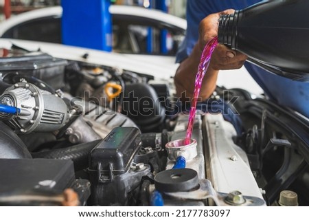 Auto mechanic filling pre-mixed long life coolant fluid in to aluminum radiators. Royalty-Free Stock Photo #2177783097