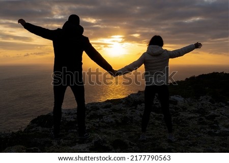 Unrecognizable couple holding hands on the Dingli Cliffs at sunset.