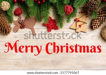 Merry Christmas text. Top view of Christmas toys, decorations and fir tree branches on wooden background. New Year holiday concept with copy space.