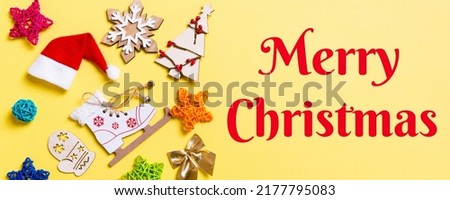 Merry Christmas text. Top view Banner of Christmas decorations and Santa hats on yellow background. Happy holiday concept with copy space.