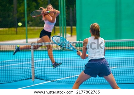 A girl plays tennis on a court with a hard blue surface on a summer sunny day Royalty-Free Stock Photo #2177802765