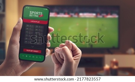 Live in-play betting app on smartphone display, a woman is betting at home and winning, POV shot Royalty-Free Stock Photo #2177823557