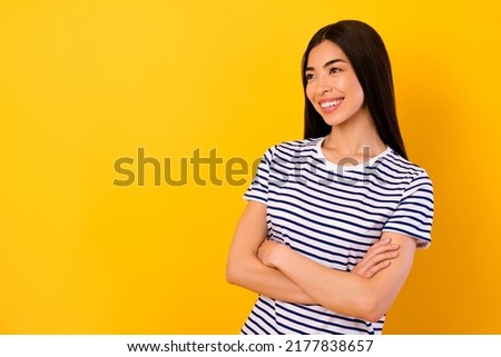 Photo of stunning dreamy girl dressed striped clothes arms crossed looking empty space isolated yellow color background
