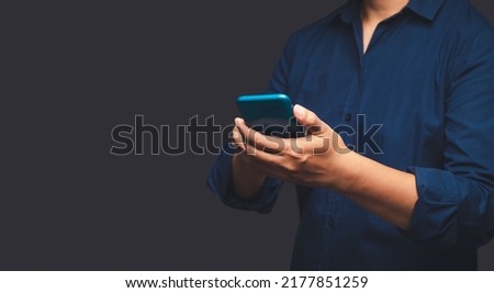 Close-up of hands businessman in a suit using a mobile phone while standing on a gray background. Space for text. Technology and communication concept