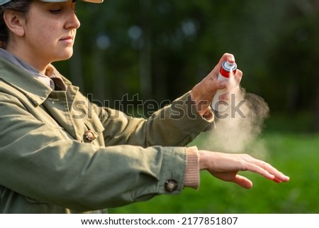 health care, protection and people concept - woman spraying insect repellent or bug spray to her hand at park Royalty-Free Stock Photo #2177851807