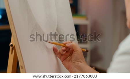 Hand of professional artist drawing vase model design with pencil on white canvas and wooden easel. Using creative skills and artistic tools to create outline sketch with inspiration. Close up. Royalty-Free Stock Photo #2177863003
