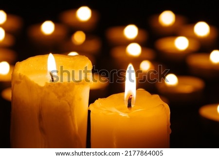 Two burning candles in the dark against the background of blurry lights