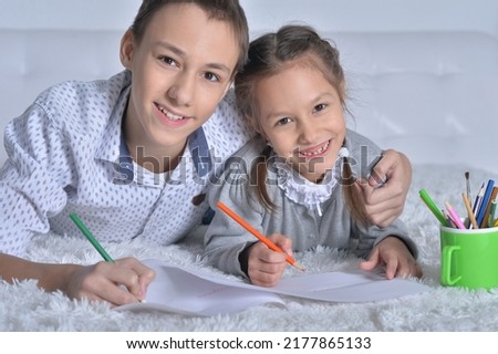 Portrait of brother and sister painting lying on the bed