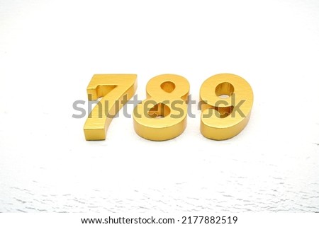  Number 789 is made of gold painted teak, 1 cm thick, laid on a white painted aerated brick floor, visualized in 3D.                                          