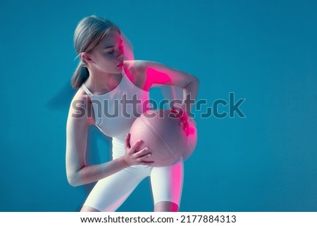 Female basketball player moving holding ball in pink neon light. Long exposure. Copy space. Energetic sports workout Royalty-Free Stock Photo #2177884313