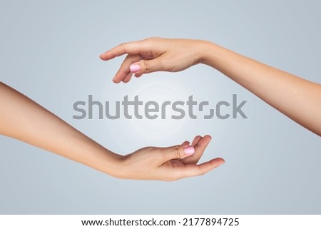 Close-up of the female hands of a young women holding a light ball isolated on a gray-blue background. Energy exchange. Spirituality, awakening, enlightenment	