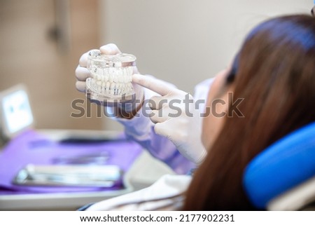 Dentist showing teeth model and discussing with patient about human teeth with gums. Knowledge about caring for healthy teeth. Medical treatment at modern dental clinic or dentist office. Royalty-Free Stock Photo #2177902231