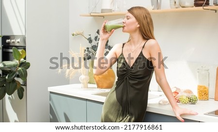 An attractive blonde is drinking a green smoothie in the kitchen. Healthy eating, detoxification. Royalty-Free Stock Photo #2177916861