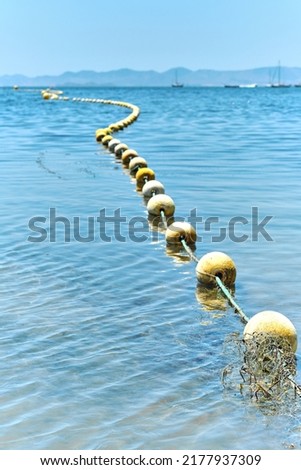 Vertical shot of Mediterratean seascape with floating buoys, rope dividing area on beach. Clear blue water, sunny summer day. Costa Blanca. Spain
