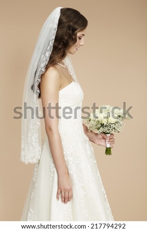Beautiful young bride in wedding dress holding bouquet 
