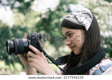 Young Asian teeage girl take a photo and lookihg on camera in the park