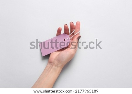 Female hand with a price tag on a gray background
