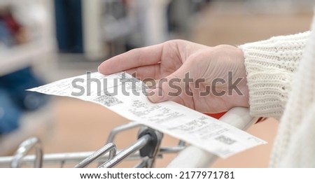 A smiling woman checking her shopping receipt isolated on white background Royalty-Free Stock Photo #2177971781