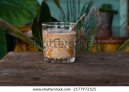 Glass of Cappuccino, cup of coffee with milk and ice on the tropical background.