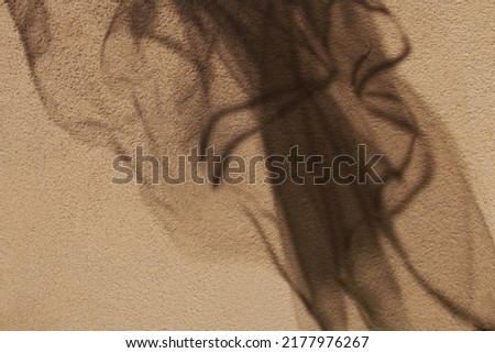Fabric shadow. Against the background of a textured wall. Beige color.