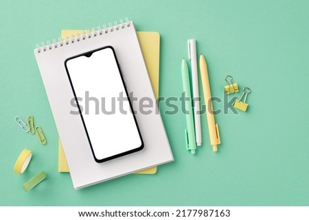 Back to school concept. Top view photo of school supplies smartphone on notepad pens binder clips and adhesive tape on isolated pastel green background with copyspace Royalty-Free Stock Photo #2177987163