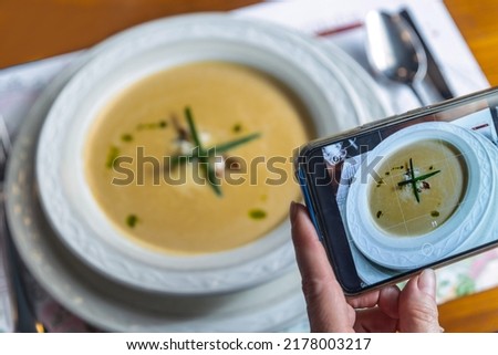 Phone photography of food. Woman hands take photo of cream soup with smartphone for social media
