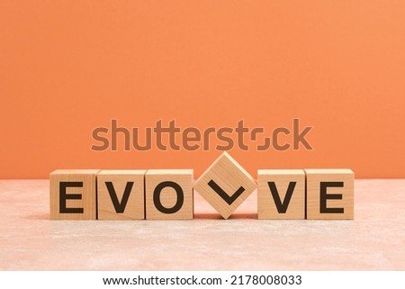 Evolve text on a wooden blocks on wooden table, brown background