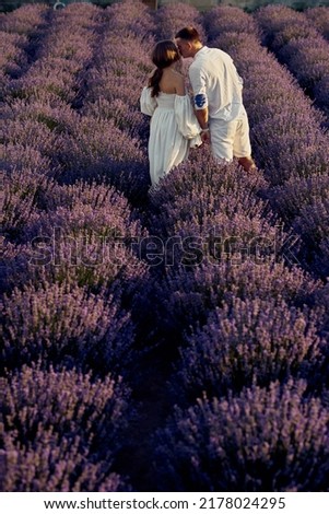 young beautiful pregnant couple walking on a lavender field at sunset. Happy family concept
