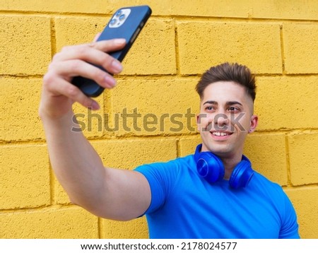 Young caucasian boy taking a selfie on a yellow wall. Portrait.