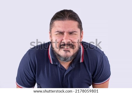 A middle aged man without glasses squinting and leaning forward in an attempt to focus clearly at something. Poor eyesight and nearsightedness to due to aging. Isolated on a white backdrop. Royalty-Free Stock Photo #2178059801