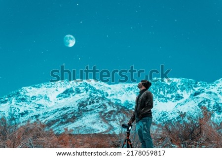 young latin photographer in the snow at night taking pictures of the stars