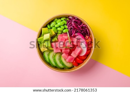 Ahi poke with tuna, avocado, edamame, cabbage and cucumber on pink yellow background top view Royalty-Free Stock Photo #2178061353