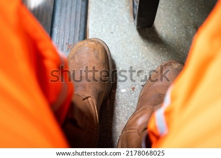 A worker is wearing safety shoe, preparing to start working at high risk workplace. Industrial safety working scene concept photo. Close-up and selective focus.