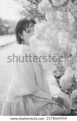 Monochrome Japanese woman crouching and posing next to rape blossoms