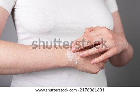 Woman applying pain relief gel on sprained wrist for swelling and inflammation reduction. Arm injury, chronic disease. Health care concept. High quality photo
