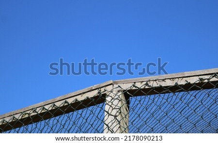 Enclosure background showing netted cage against deep blue sky with copy space